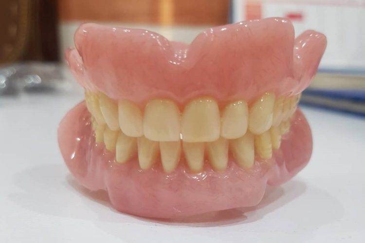 upper and lower denture false teeth on white surface