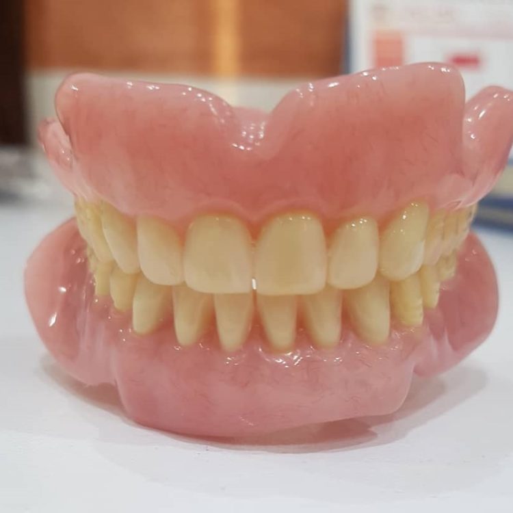 upper and lower denture false teeth on white surface