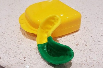 green and yellow mouthguard resting on case